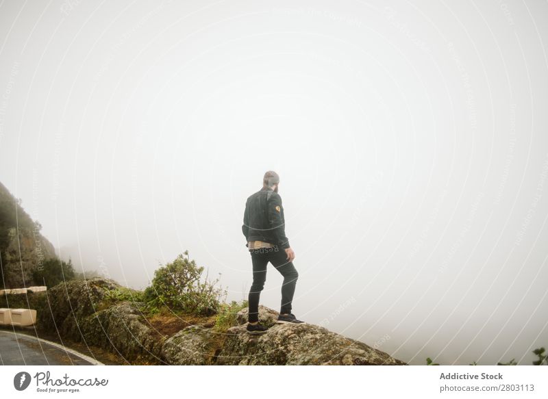 Anonymous man standing on cliff near countryside road Man Fog Landscape Street Cliff Spain playa norte Rock Vacation & Travel explore admiring Weather Trip