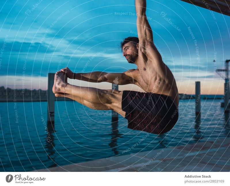 Athletic man balancing on gymnastic rings Man sportsman Balance Embankment Ring shirtless Water City Evening Youth (Young adults) upped legs Sports Action