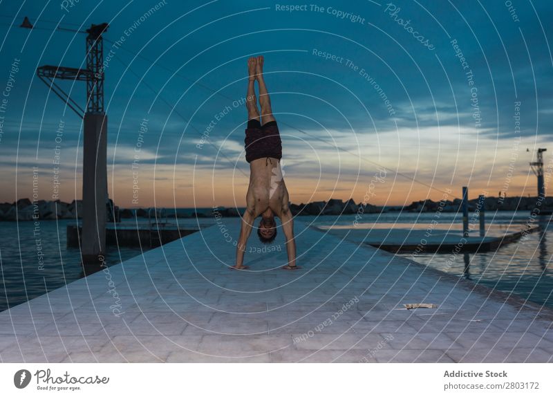 Athletic man balancing on hands on embankment Man sportsman Balance Handstand Jetty Embankment shirtless Sky Water City Amazing Evening Youth (Young adults)