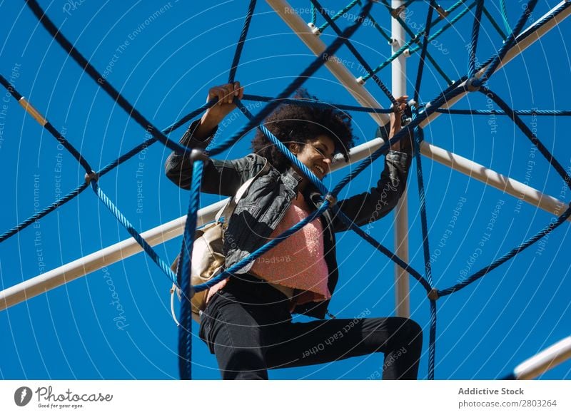 Woman with afro hair climbing by children's attractions. Action African Afro Black Cheerful Infancy Climbing Cute Equipment Family & Relations Joy Girl Happy