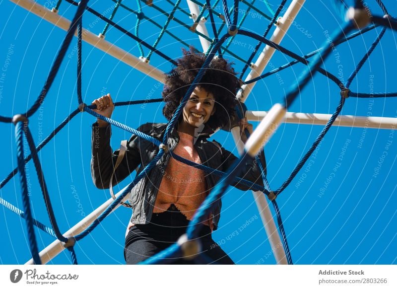 Woman with afro hair climbing by children's attractions. Action African Afro Black Cheerful Infancy Climbing Cute Equipment Family & Relations Joy Girl Happy