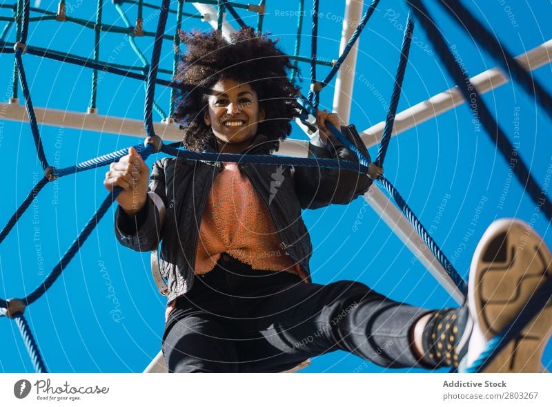 Woman with afro hair climbing by children's attractions. Action African Afro Black Cheerful Infancy Climbing Cute Equipment Family & Relations Joy Girl Happy