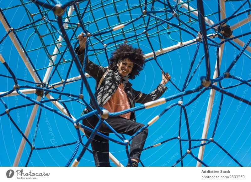 Woman with afro hair climbing by children's attractions. Action African Afro Black Cheerful Infancy Climbing Cute Equipment Family & Relations Joy Girl Happy