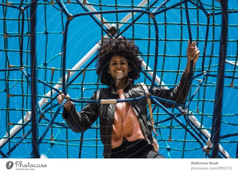 Woman with afro hair climbing by children's attractions. Action African Afro Black Cheerful Infancy Climbing Cute Equipment Family & Relations Joy Girl Happy