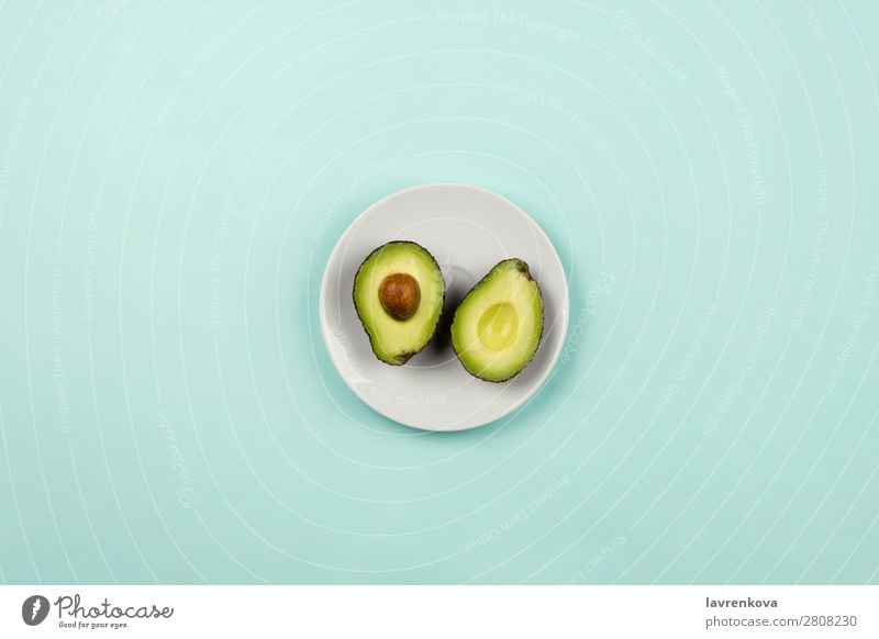 Cut avocado on white plate on pastel background Slice Natural Raw Fresh Green Mature Organic Nutrition Vegetarian diet Vegan diet Fruit Eating flat lay Plate