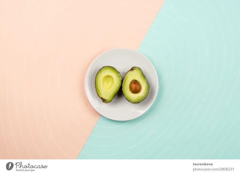 Cut avocado on white plate on pastel background Slice Natural Raw Fresh Green Mature Organic Nutrition Vegetarian diet Vegan diet Fruit Eating flat lay Plate