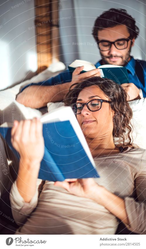 Young couple reading book on couch at home Book Home Literature Sofa Leisure and hobbies closeness Attractive Denim Vantage point Sit Day Life Adults fondness