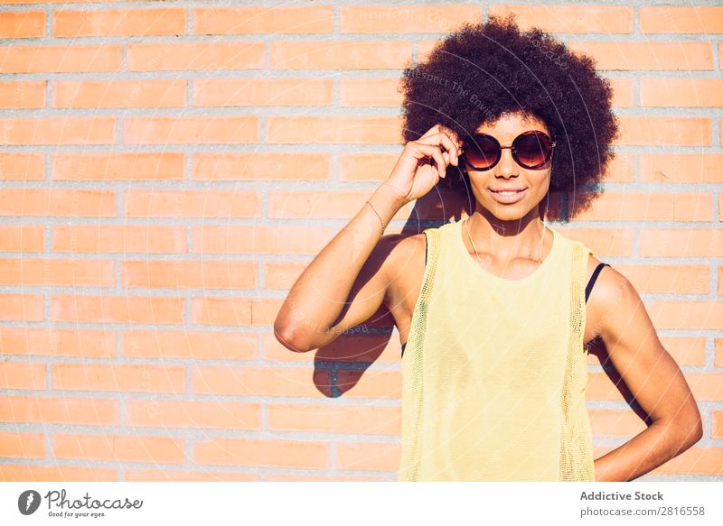 Young beautiful Afro-American woman posing and smiling while standing against brick wall African Charming Brick Model Hand Attractive Curly Sincere Happiness