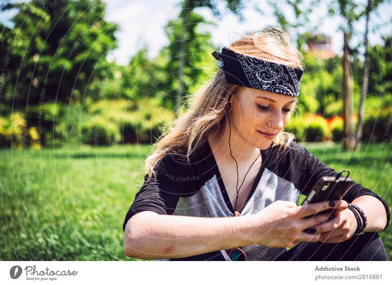 Woman skateboarder listening music from smart phone in a park Music Headphones Joy Park PDA Listening Chinese Culture Cellphone Exterior shot Young woman Sit