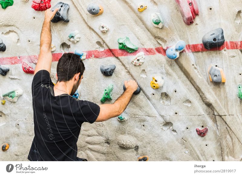 A Man practicing rock climbing on artificial wall indoors. Lifestyle Joy Leisure and hobbies Sports Climbing Mountaineering Adults Hand Fingers 1 Human being