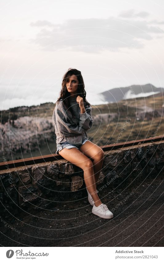 Pretty woman on handrail in mountains Woman Looking away Posture Handrail Sit Mountain Hat Vacation & Travel Top Rock Freedom Youth (Young adults) Nature