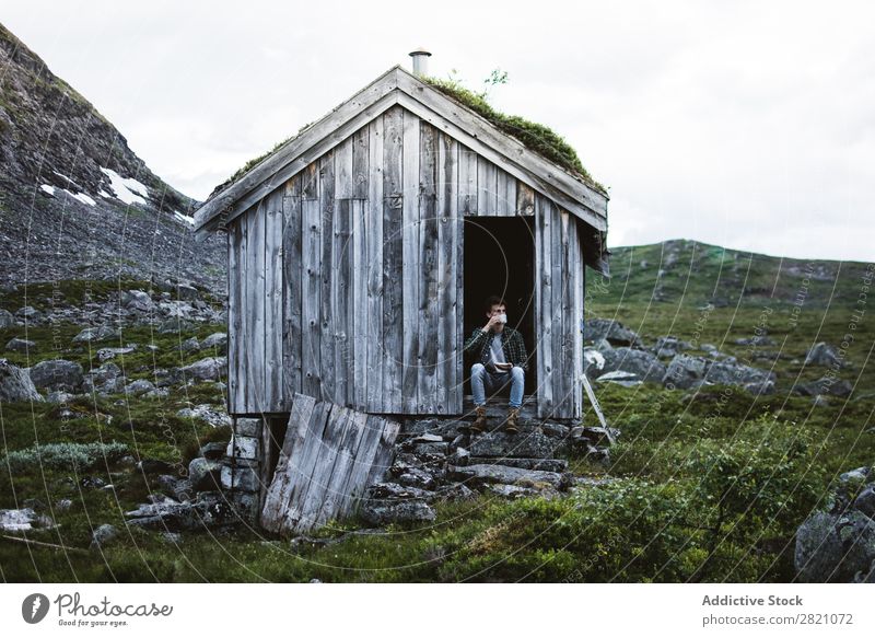 Man sitting in a old house in nature Hut Mountain Remote tranquil terrain bending House (Residential Structure) but Nature Landscape Peaceful Building Exterior