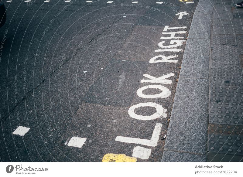 Painted words on gray ground Caution Sidewalk look right Corridor Safety London England Warning attention Communication crosswalk Public Transport Street