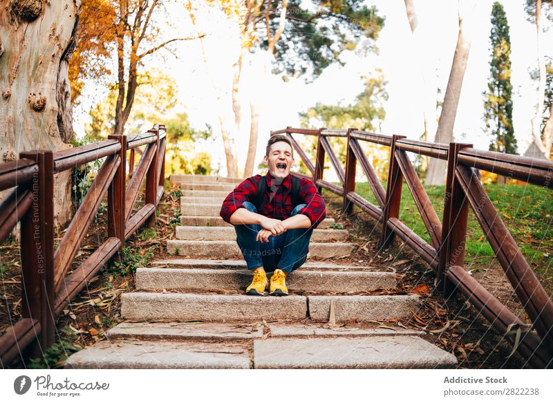 Young man sitting on steps Man Park Sit Considerate Pensive Steps Corridor Nature Human being Lifestyle Grass Leisure and hobbies Easygoing Youth (Young adults)