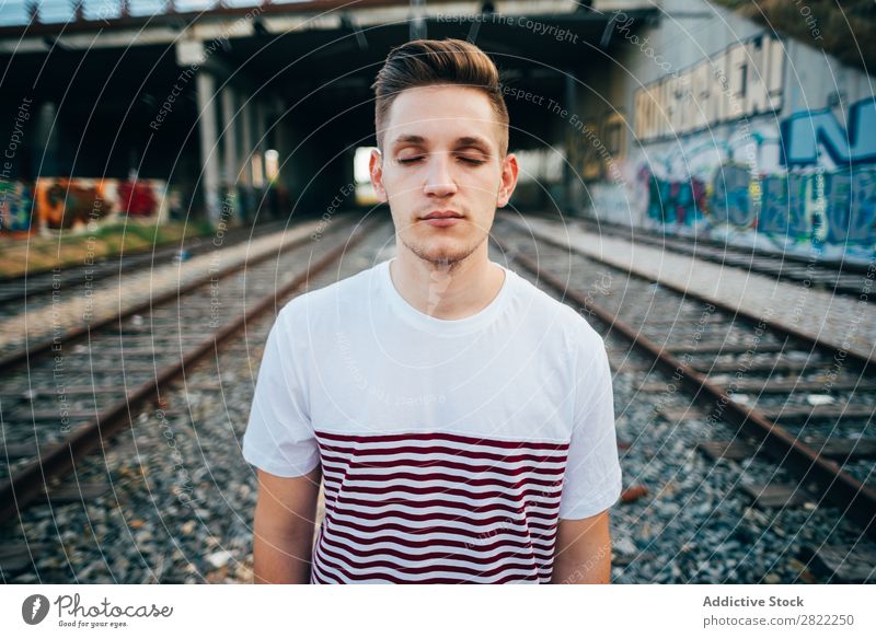 Young man at city railway Man Railroad Town Cheerful Stand Vacation & Travel Graffiti Wall (building) Transport Human being Station City Youth (Young adults)