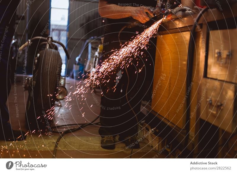 Unrecognizable worker cutting metal in garage Motorcycle Workshop Parked Engines Transport Human being Metal sparkles Vehicle Garage custom repair shop Repair