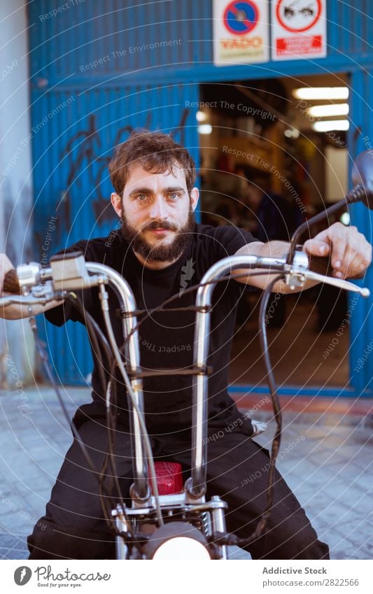 Man on bike at garage Motorcycling Looking into the camera Portrait photograph Human being bearded Motorcycle Workshop Parked Engines Transport Vehicle Garage