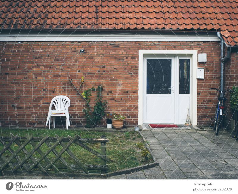 Conveniently located (with terrace!) House (Residential Structure) Gloomy Plastic chair Front door Entrance Fence Fence post Shabby Roof Brick Brick wall