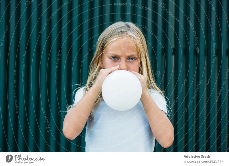 Girl blowing balloon outside Balloon Blow Posture Earnest Unemotional Town Infancy inflating Birthday Youth (Young adults) Portrait photograph Party facial