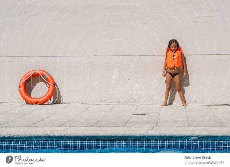 Cheerful girl posing in life vest Girl poolside Posture Summer Swimwear Inflatable Resort Vacation & Travel Swimsuit Relaxation Vest Swimming pool Child