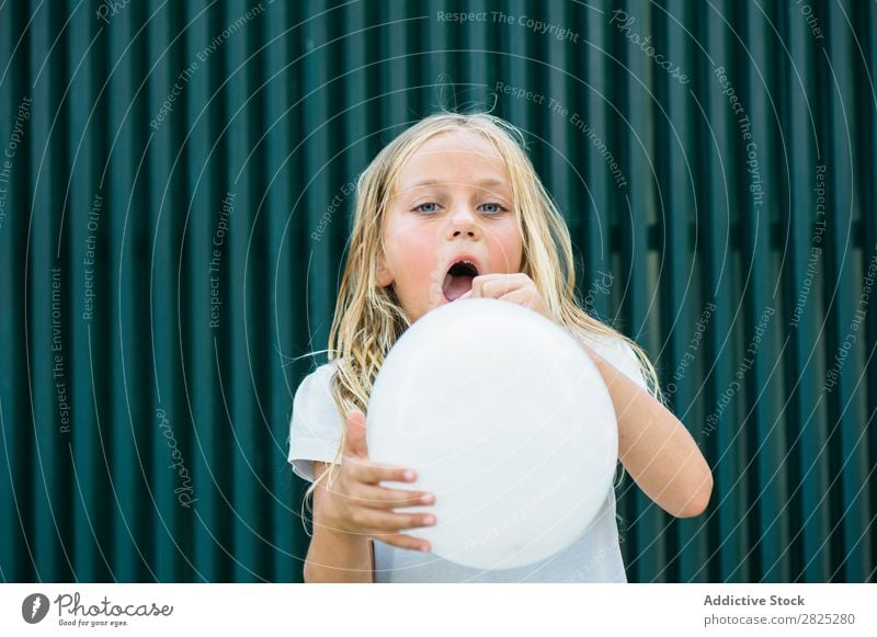 Girl blowing balloon outside Balloon Blow Posture Earnest Unemotional Town Infancy inflating Birthday Youth (Young adults) Portrait photograph Party facial