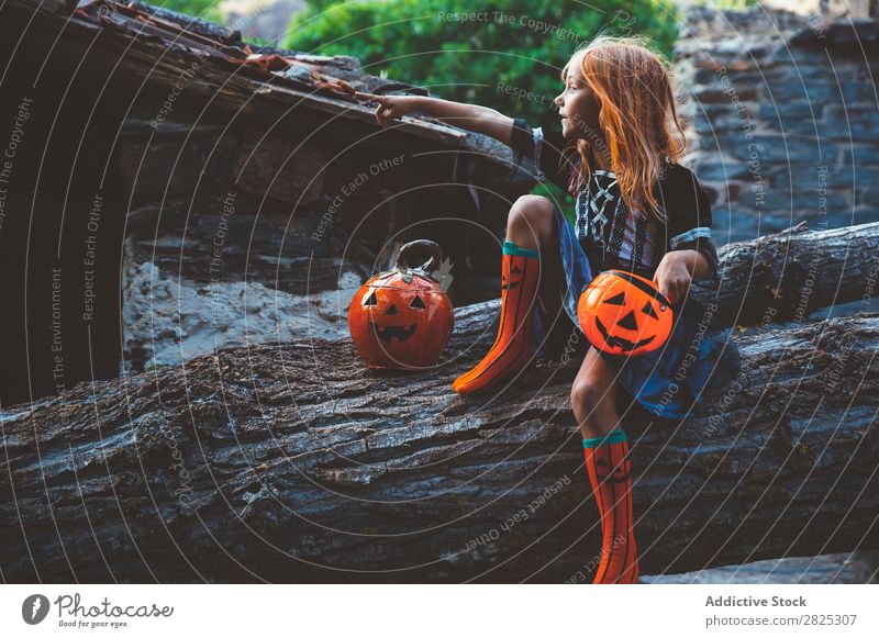 Cheerful kid in costume posing on tree Girl Costume Hallowe'en Posture Feasts & Celebrations Tradition Magic Expression Candy Clothing Tree trunk Festival