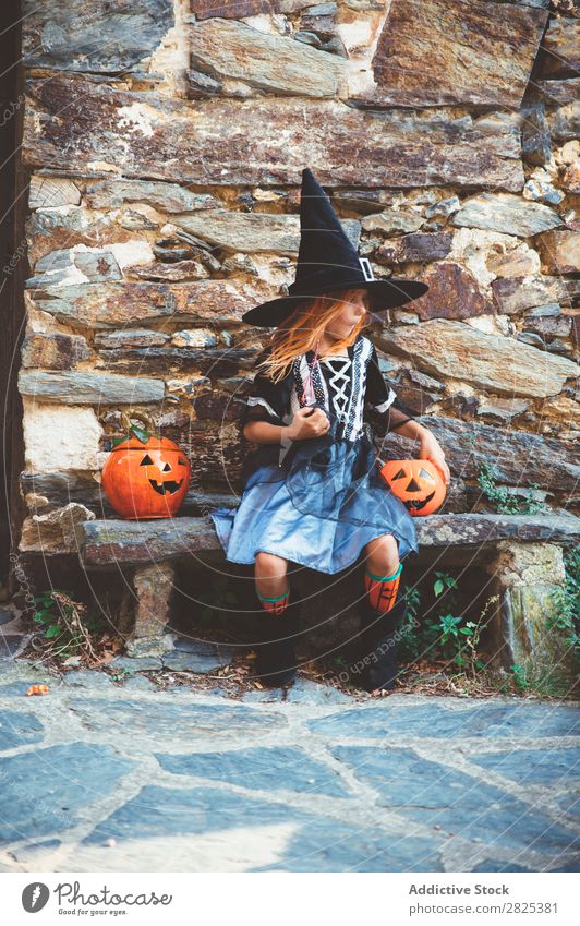 Little girl in witch costume sitting on bench Girl Hallowe'en Candy Eating Bench Dog food Vacation & Travel Entertainment Festival Seasons Costume Tradition