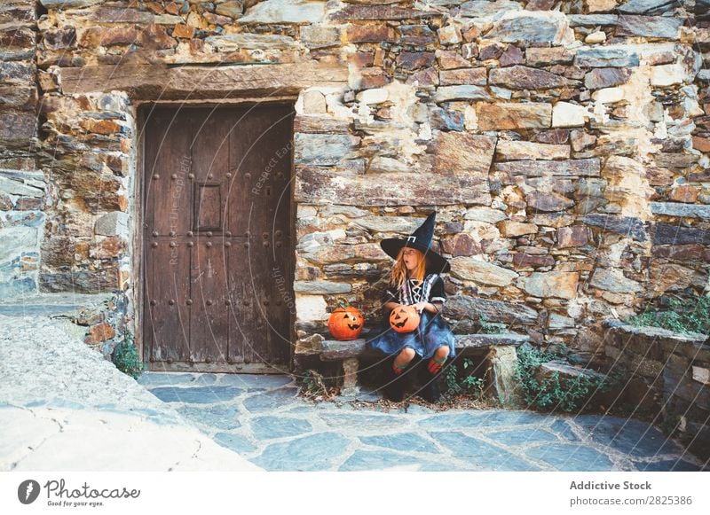 Little girl in witch costume sitting on bench Girl Hallowe'en Candy Eating Bench Dog food Vacation & Travel Entertainment Festival Seasons Costume Tradition