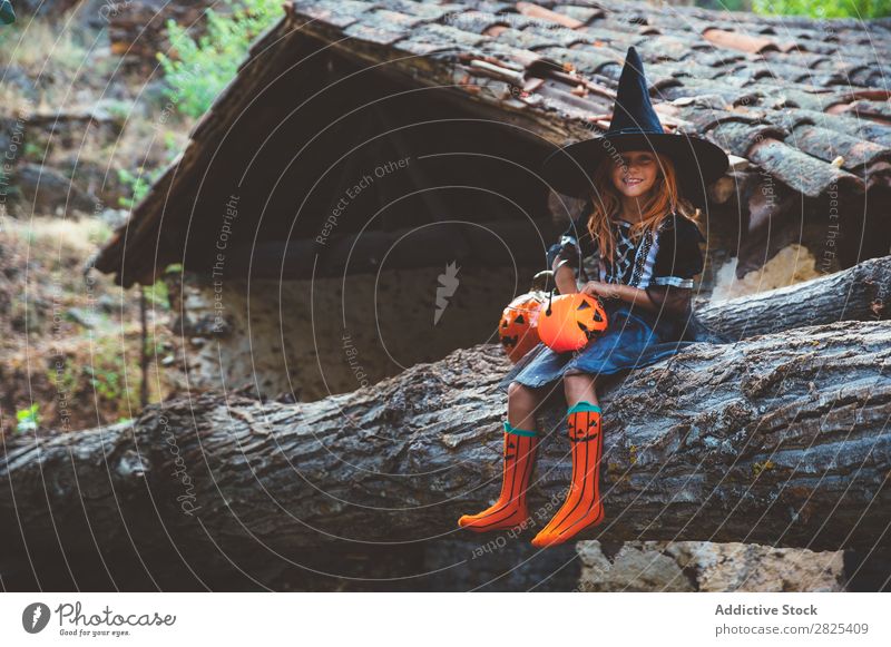 Cheerful kid in costume posing on trunk Girl Costume Hallowe'en Posture Feasts & Celebrations Tradition Magic Expression Candy Clothing Tree trunk Festival