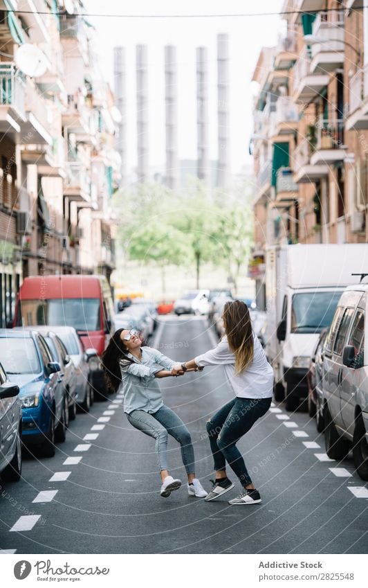 An attractive young lesbian couple on a street Woman Spinning Town having fun Hip & trendy Summer holding hands Laughter spinning round enjoyment Joy Relaxation