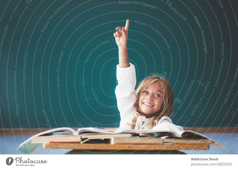 Happy schoolgirl with hand up Girl Classroom Blackboard Sit Desk Smiling Answer Cute Education School Grade (school level) Student Youth (Young adults) Study