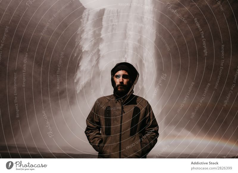 Young man in coat on waterfall Man Waterfall Rainbow Iceland Stream Fog Tourism Mountain Natural Vacation & Travel Landscape Environment Powerful Flow Energy