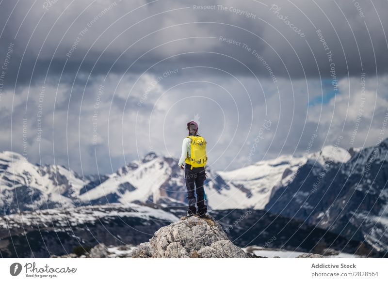 Tourist standing on stone in mountains Human being Snow Mountain Backpack Vacation & Travel Cliff Clouds Winter Hiking Adventure Landscape Nature trekking