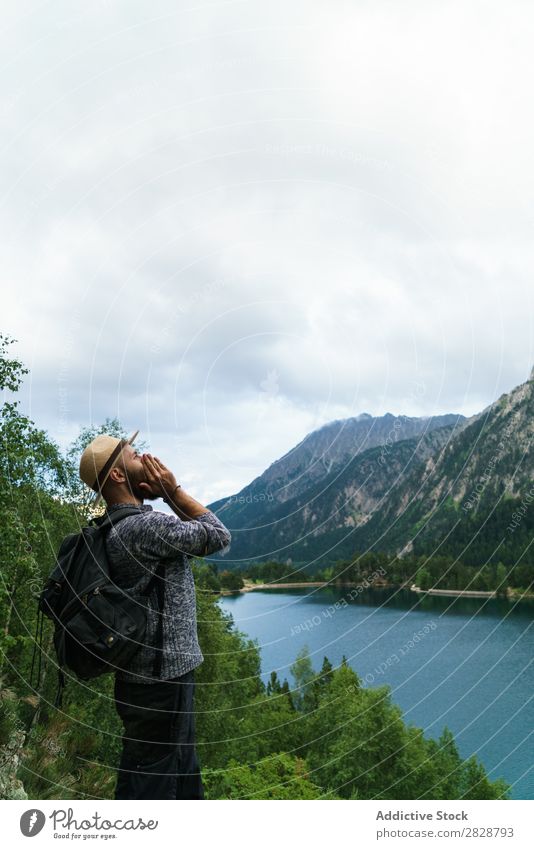 Man screaming in mountains Tourist Lake handsome bearded Nature Scream hands to mouth Freedom Vacation & Travel Lifestyle Backpack Mountain Landscape Water