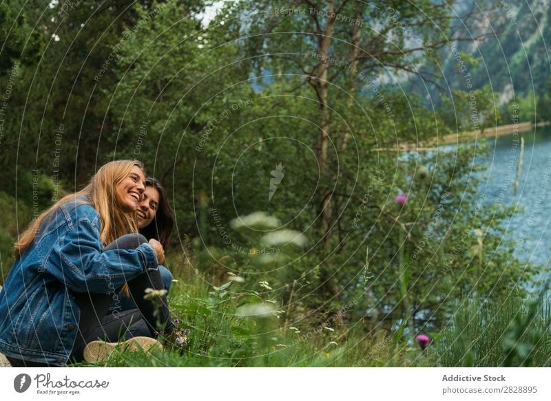 Cheerful women sitting at lake Woman Mountain Smiling Sit Together Happy Laughter Hiking Lake Water embracing Vacation & Travel Adventure Tourist