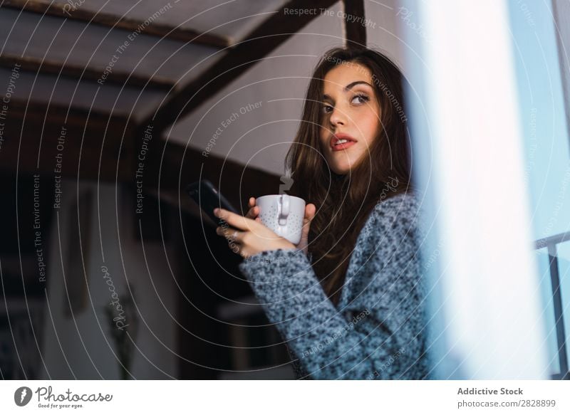 Beautiful model with cup of coffee and smartphone Woman Home Cuddling Coffee Dream human face Posture Cup Pensive Considerate Lifestyle