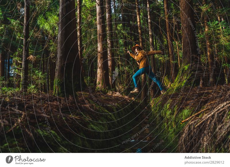 Young woman jumping over drain Woman Tourist Forest Green Nature Environment Jump Water ditch Hat Style pretty Natural Seasons Plant Leaf Light Fresh Bright Day