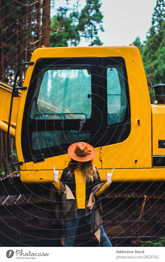 Woman posing against tractor in woods Forest Style Landscape Rock'n'Roll Tractor Gesture Rural Provocative covering face Cold Equipment Action Expression Rebel