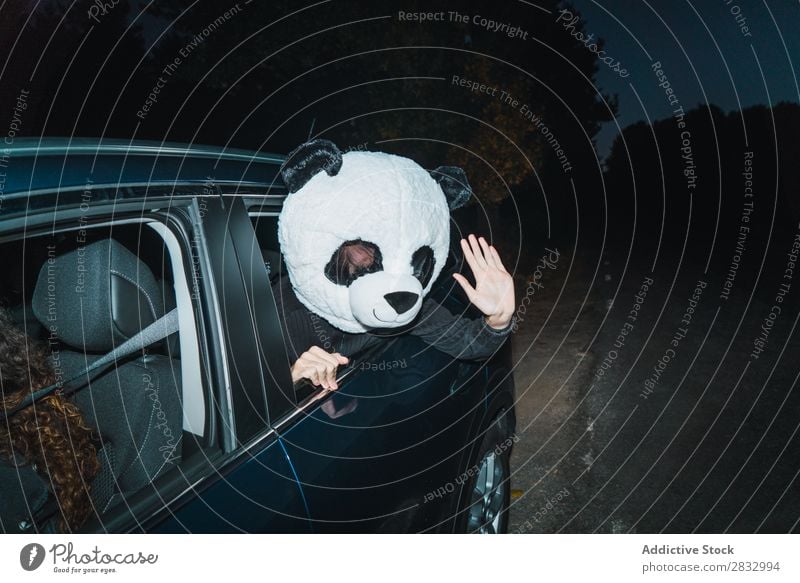 Man in panda mask leaning out of car window Mask Peace Gesture Human being Panda Indicate Back Seat Passenger compartment Car Vehicle Transport Hand