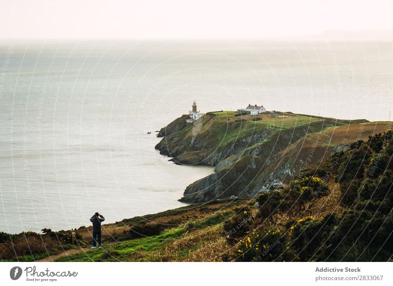 Tourist standing on rocky coast Coast seaside Rock Ocean Landscape Beach Nature Water Natural seascape Stone Beautiful Green Stand Grass Vacation & Travel