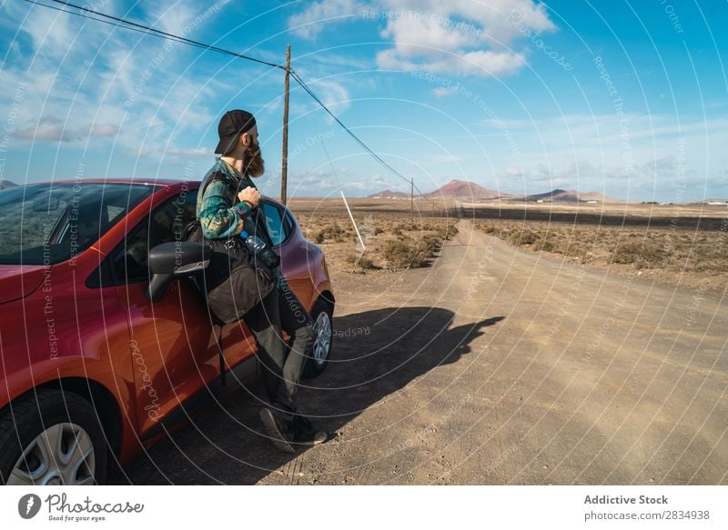 Tourist leaning on car roof Car Mountain Drive Red Stand Lean Nature Street Landscape Natural Rock Stone Lanzarote Spain Vantage point Vacation & Travel Tourism