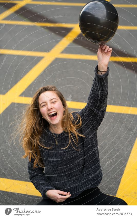 Woman having fun with black balloon pretty Balloon Black Laughter Cheerful mouth opened Parking lot Wrinkle Ground Yellow Portrait photograph