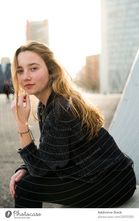 Pretty young woman looking at camera and  sitting in the street. outdoors shot. dreamy thoughtful pensive looking away touching lips city urban pretty beautiful