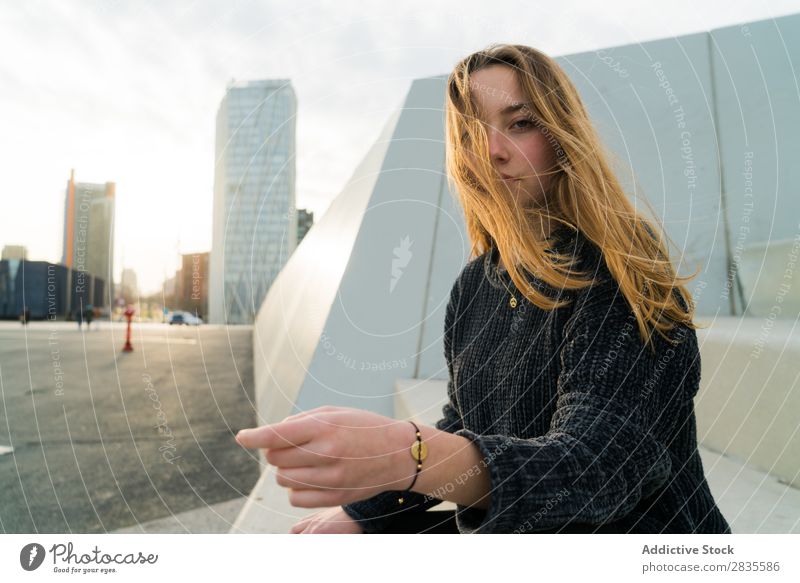 Pretty young woman looking at camera and  sitting in the street. outdoors shot. dreamy thoughtful pensive looking away touching lips city urban pretty beautiful