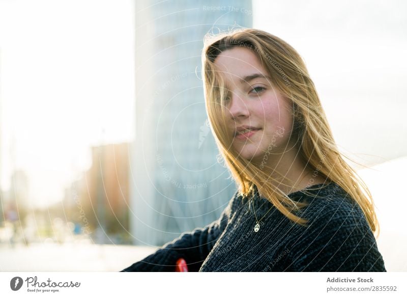 Pretty young woman looking at camera and  sitting in the street. outdoors shot. dreamy thoughtful pensive looking away touching lips city urban pretty beautiful