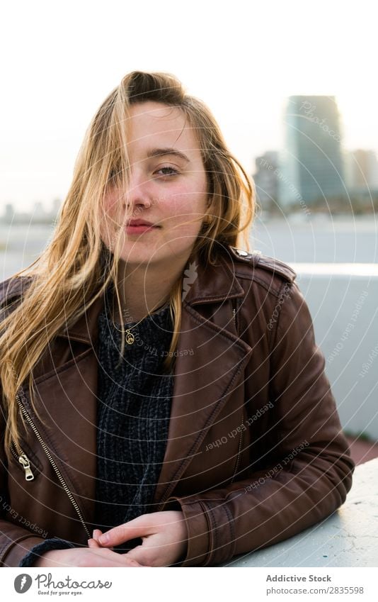 Pretty young woman looking at camera and  sitting in the street. outdoors shot. dreamy thoughtful pensive looking away touching lips city urban pretty beautiful