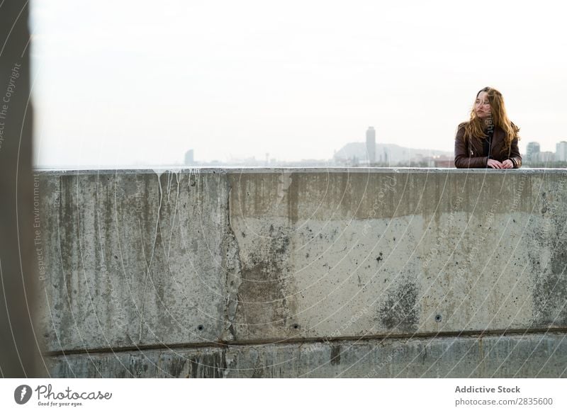 Young girl at the concrete block Woman Concrete Block Lean Looking away Town Street City Building Dream Smiling Flying Hair Considerate Pensive pretty