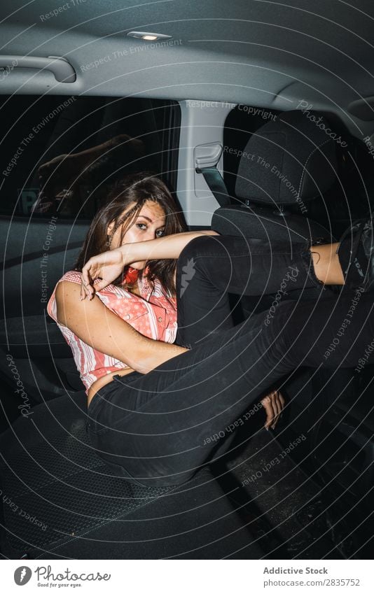 Woman in light posing in car Provocative Car Posture Attractive covering mouth Style Interior shot Dark Self-confident Vehicle Easygoing Night Passenger Light