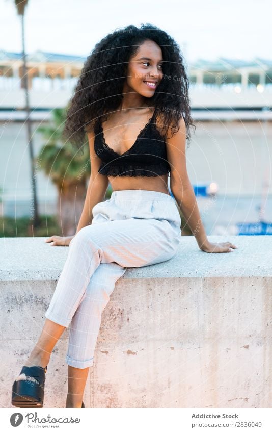 Pretty woman sitting on evening street Woman pretty Youth (Young adults) Portrait photograph Looking into the camera Black African Sit Fence Concrete Evening