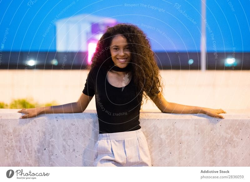 Laughing woman leaning on fence Woman Cheerful Town Posture Ethnic Self-confident Expressive Twilight Street Dusk Lovely Portrait photograph Dream Wonderful